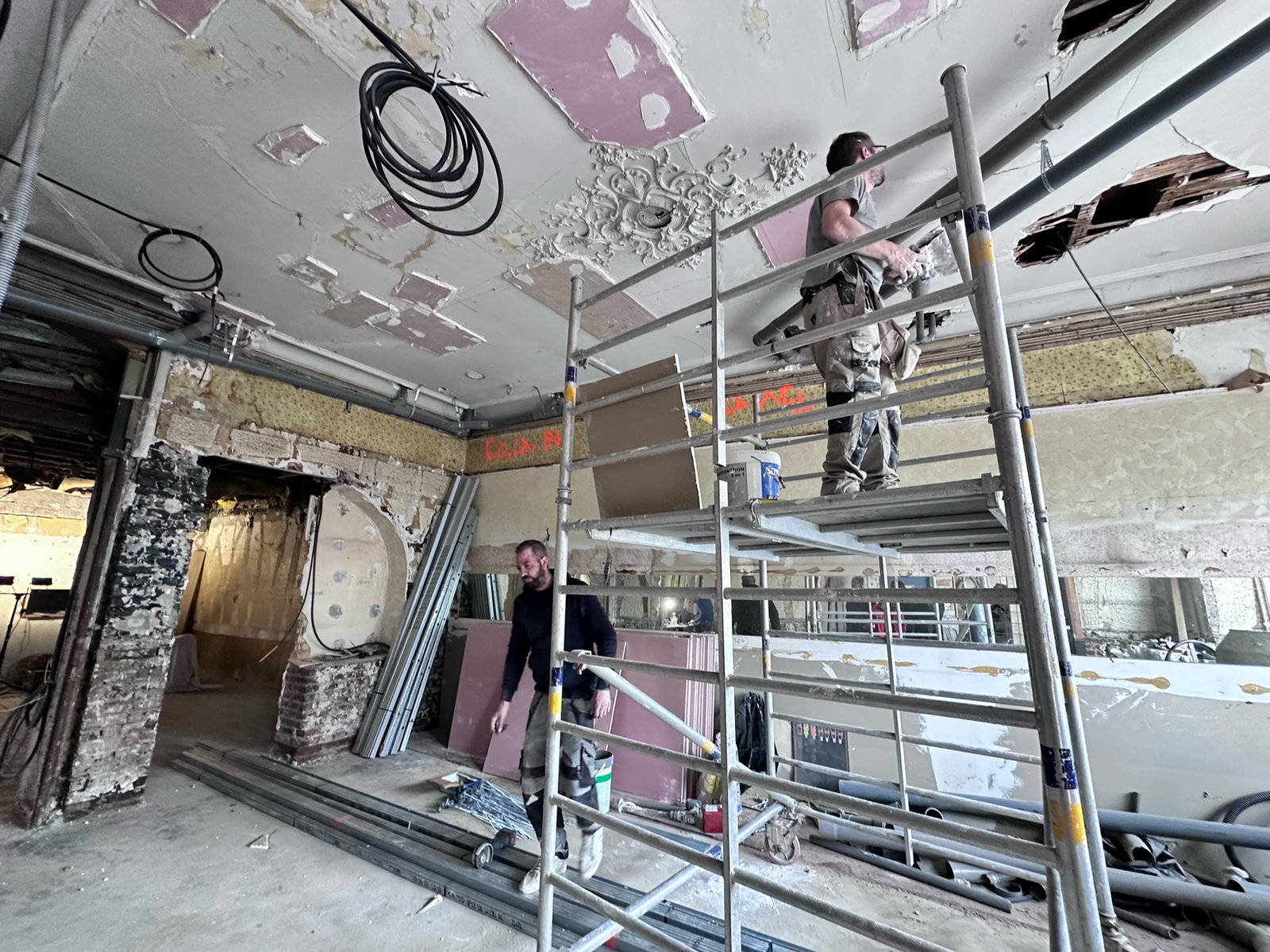 Chantier de réhabilitation en cours : échafaudage sous un plafond mouluré