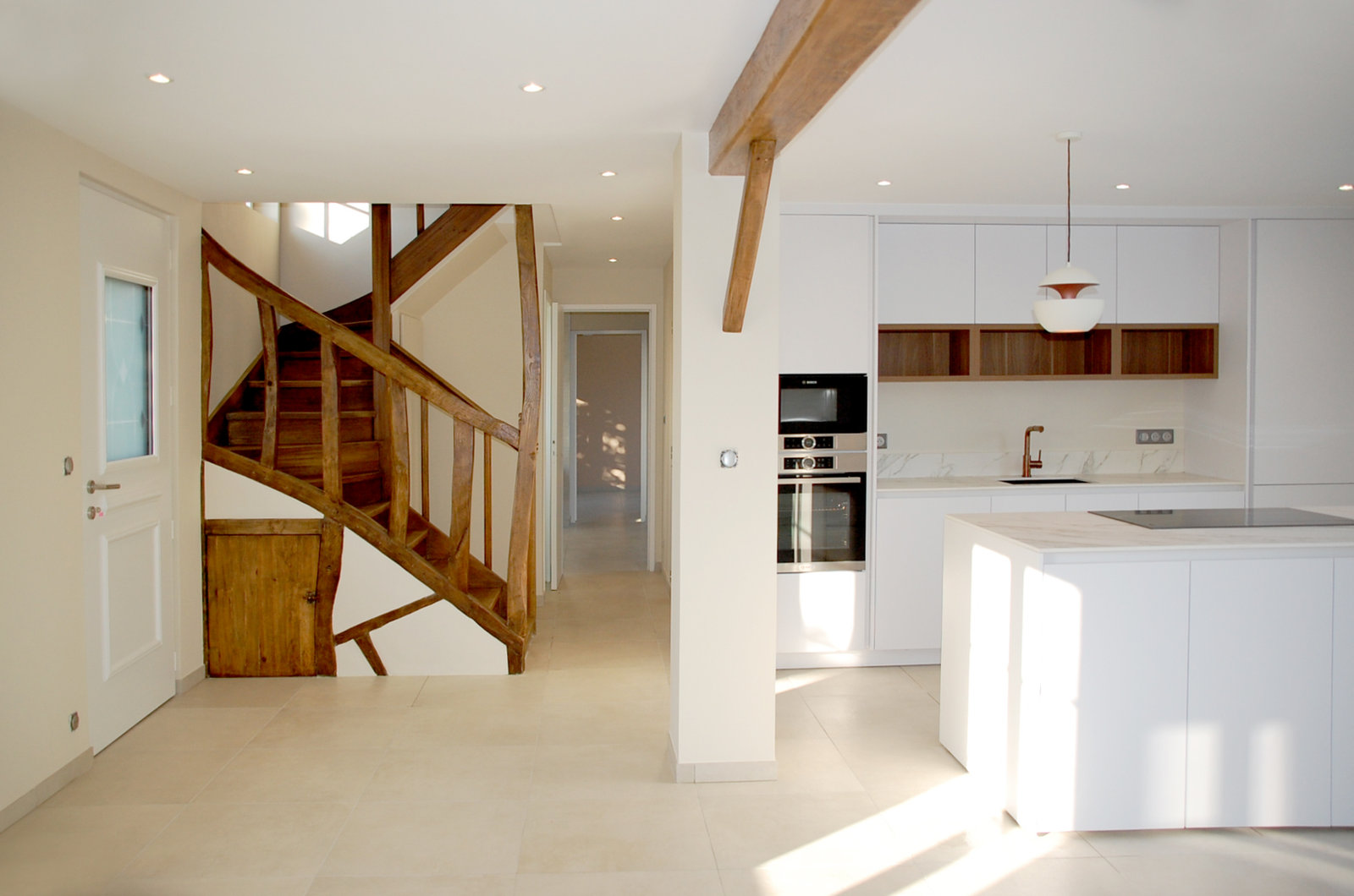 Cuisine blanche ouverte sur un escalier de bois